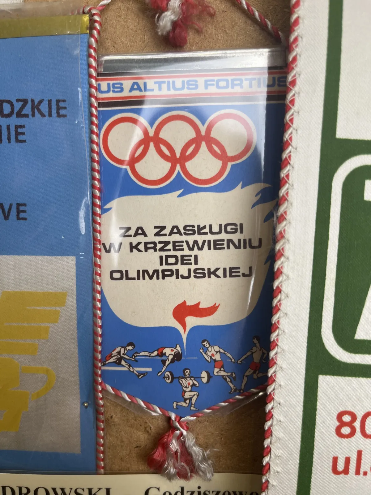 Proporczyk za zasługi w krzewieniu idei olimpijskiej z symbolami sportów olimpijskich.
